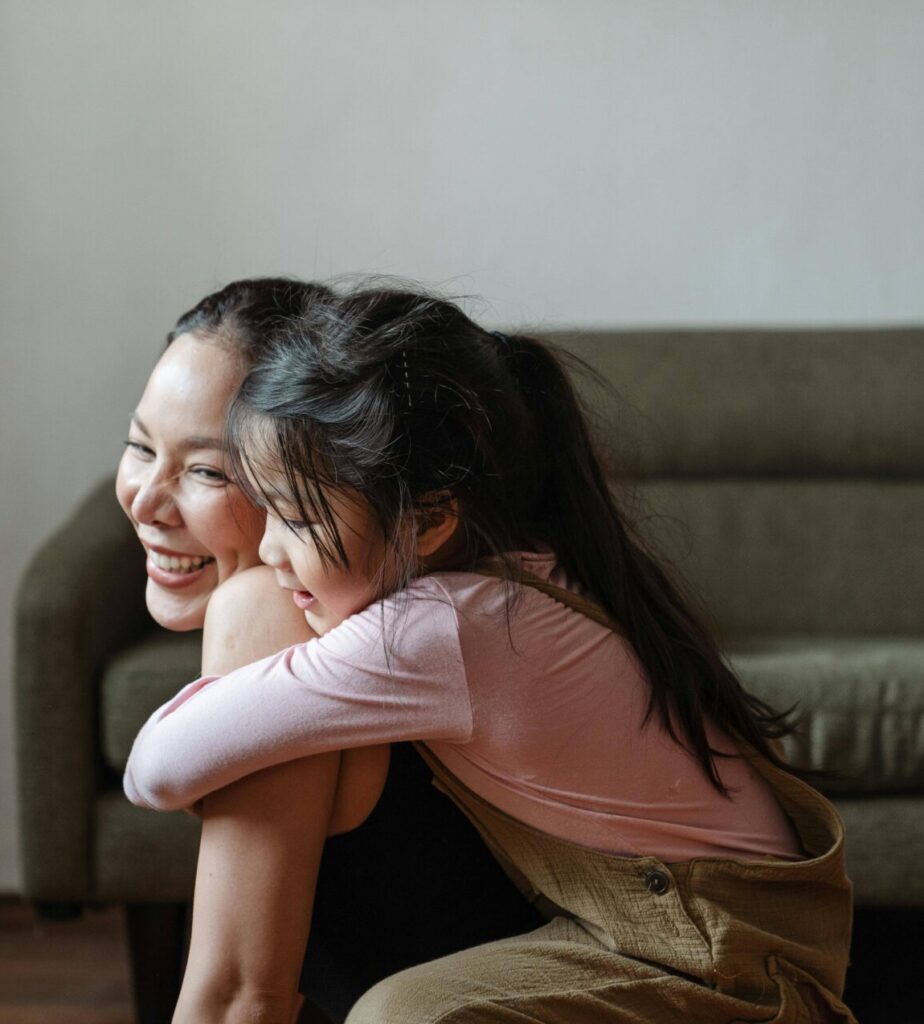 Asian mom smiling with kid on her back while she does yoga